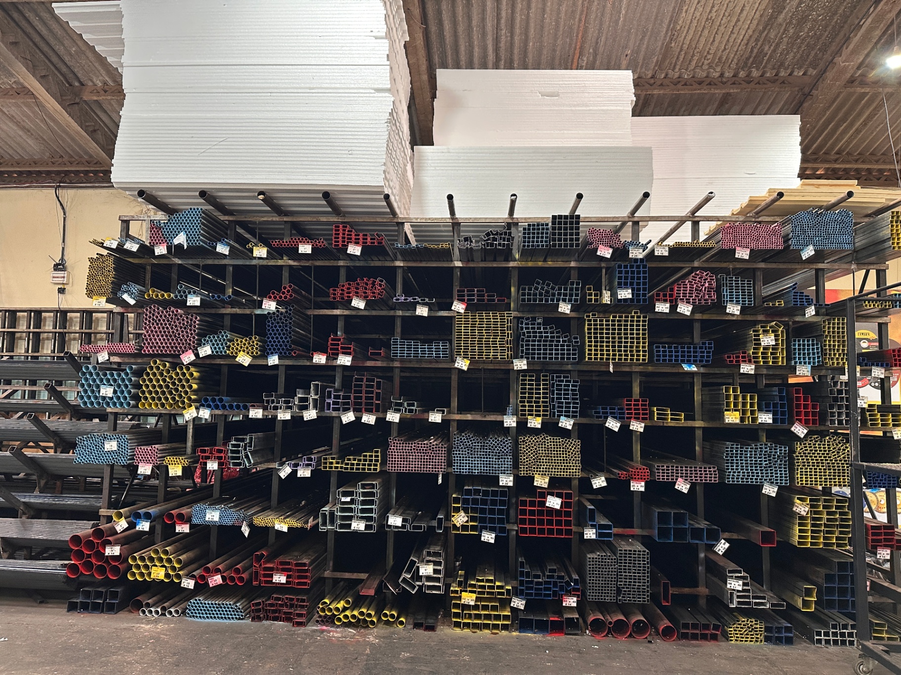 Telhas metálicas e materiais organizados no interior da HM Metais.